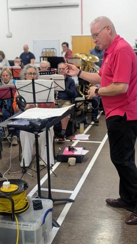 Tom Milford conducting with clarinets and tuba in the background